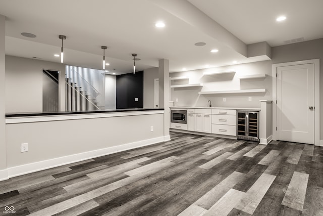 unfurnished living room with beverage cooler, sink, and dark wood-type flooring