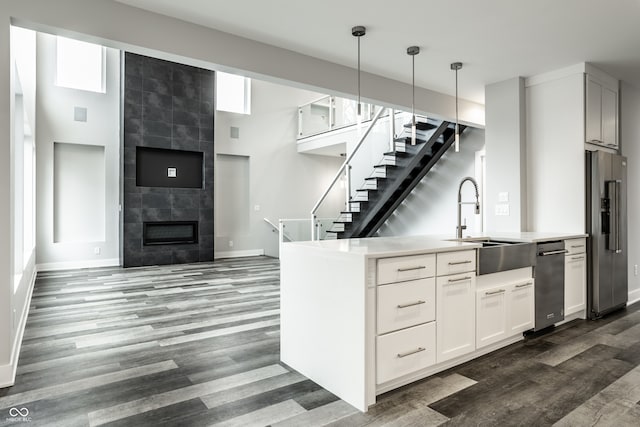 kitchen featuring a high ceiling, dark hardwood / wood-style floors, hanging light fixtures, appliances with stainless steel finishes, and a fireplace