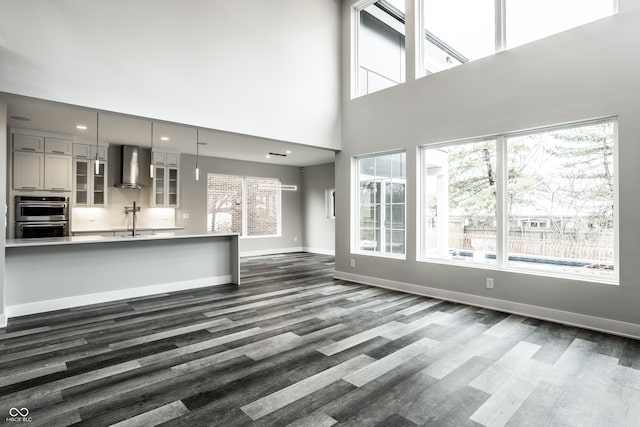 unfurnished living room with sink, hardwood / wood-style floors, plenty of natural light, and a high ceiling