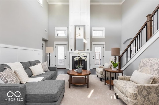 living room with a high ceiling, wood-type flooring, and ornamental molding