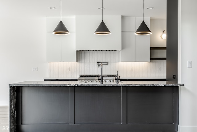 kitchen with decorative light fixtures, tasteful backsplash, and light stone countertops