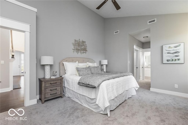 carpeted bedroom with ensuite bathroom, ceiling fan, and high vaulted ceiling