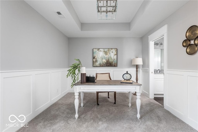 home office with carpet floors and a raised ceiling