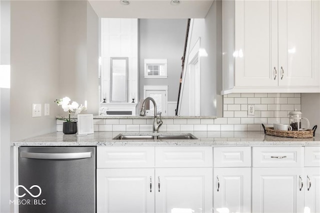 kitchen with tasteful backsplash, white cabinets, dishwasher, light stone counters, and sink