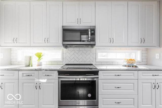 kitchen with white cabinetry, stainless steel appliances, light stone counters, and tasteful backsplash