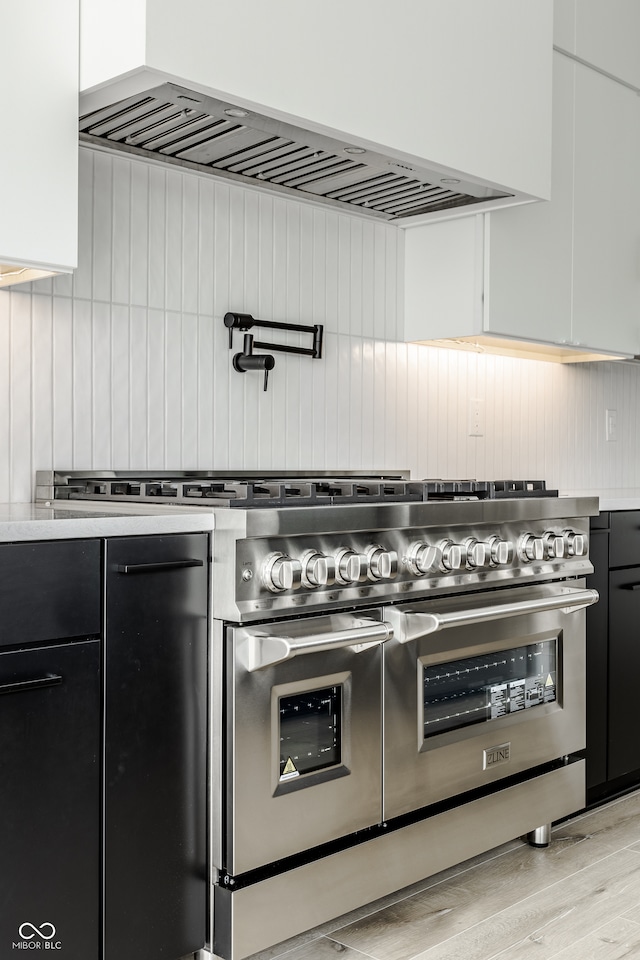 kitchen featuring white cabinetry, light wood-type flooring, and range with two ovens