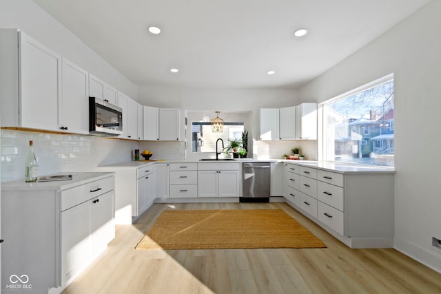 kitchen with appliances with stainless steel finishes, light hardwood / wood-style floors, and a wealth of natural light