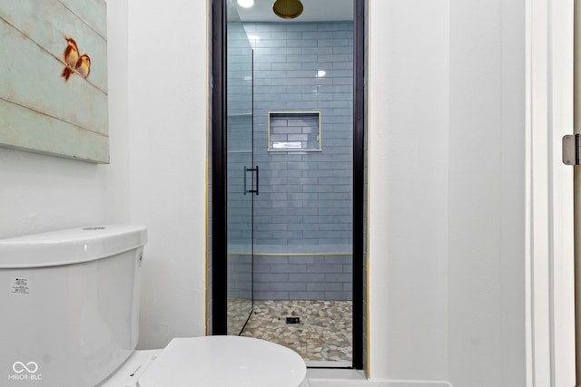 bathroom featuring toilet and a shower with door