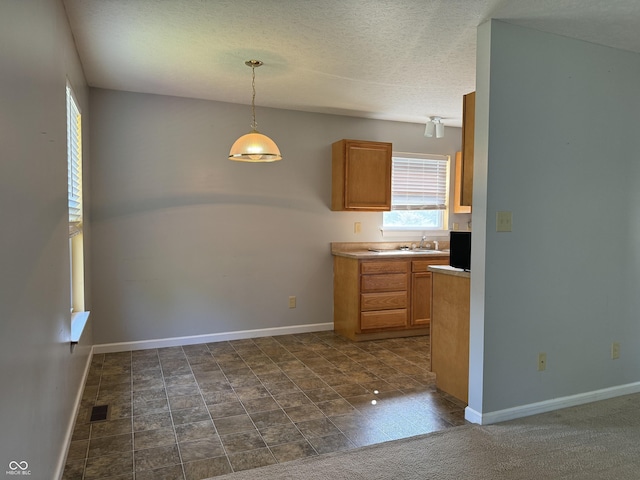 kitchen with hanging light fixtures, sink, and a textured ceiling