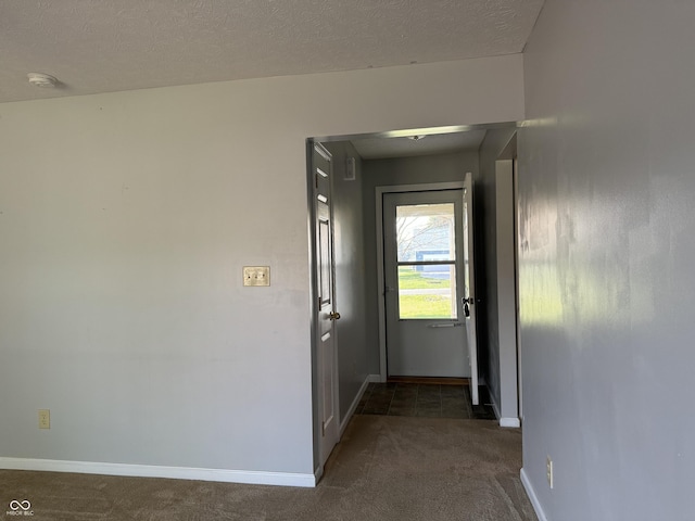 corridor featuring dark carpet and a textured ceiling