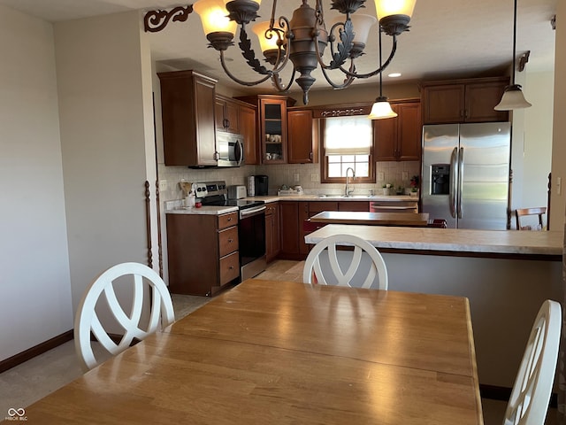 kitchen with stainless steel appliances, light countertops, hanging light fixtures, glass insert cabinets, and a sink