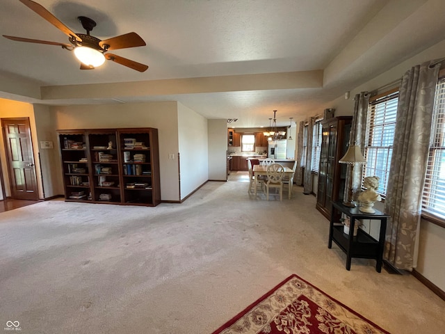 living room with ceiling fan with notable chandelier, a healthy amount of sunlight, and light colored carpet