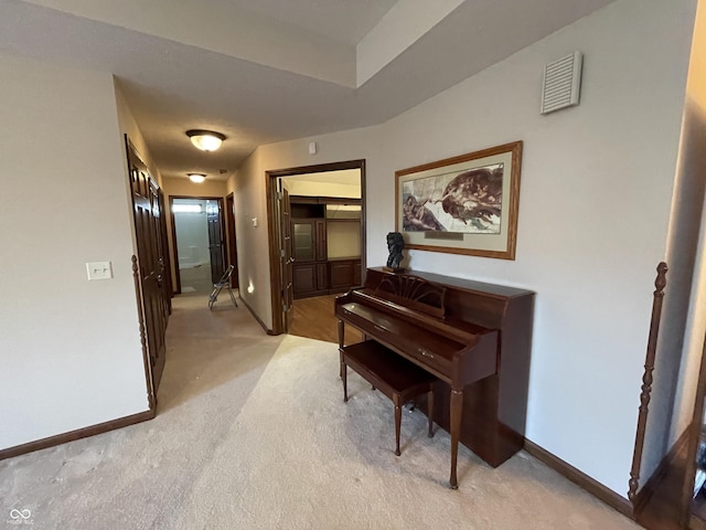 hall with light carpet, visible vents, and baseboards