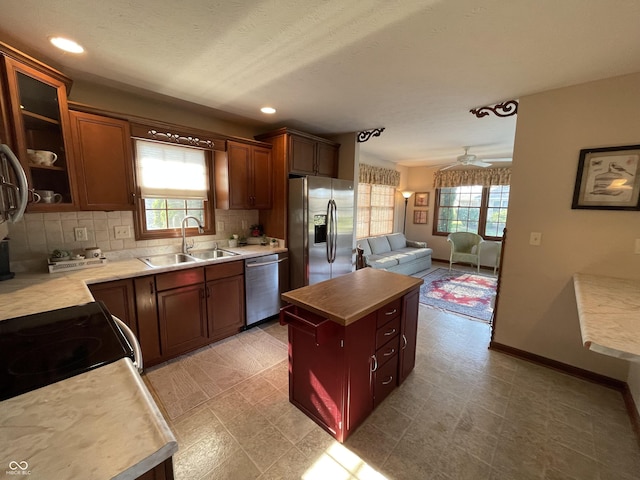 kitchen with appliances with stainless steel finishes, light countertops, a sink, and a center island