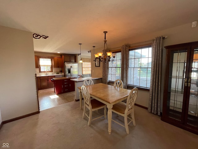 dining space featuring light tile patterned flooring, plenty of natural light, sink, and a chandelier