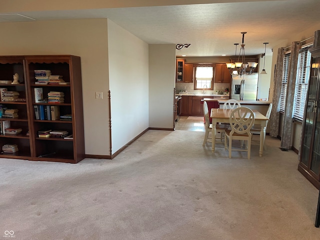 dining room featuring a notable chandelier, sink, and light carpet