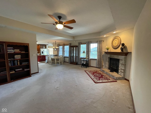 carpeted living room with ceiling fan, a fireplace, and a tray ceiling