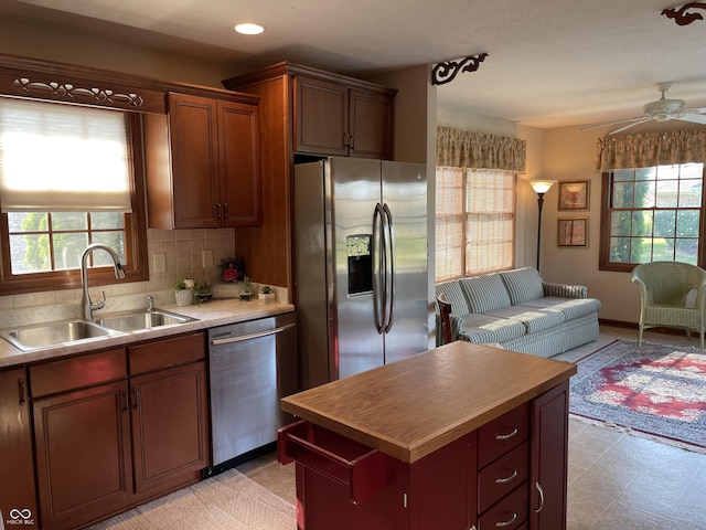 kitchen with stainless steel appliances, light countertops, backsplash, open floor plan, and a sink