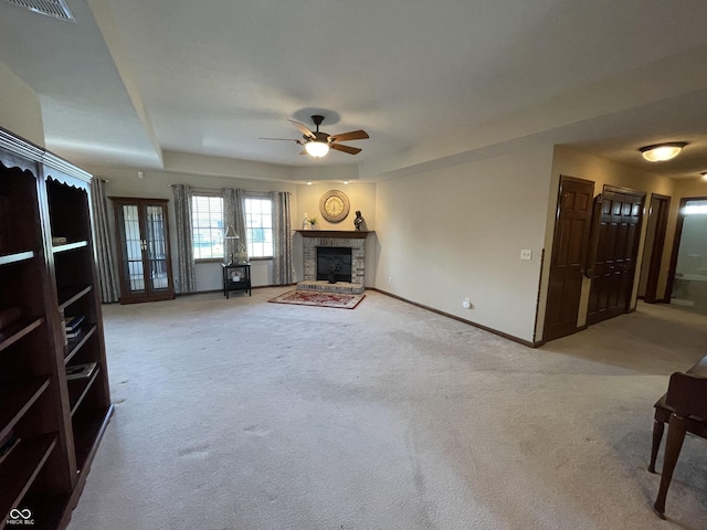 unfurnished living room with a fireplace with raised hearth, baseboards, visible vents, and light colored carpet