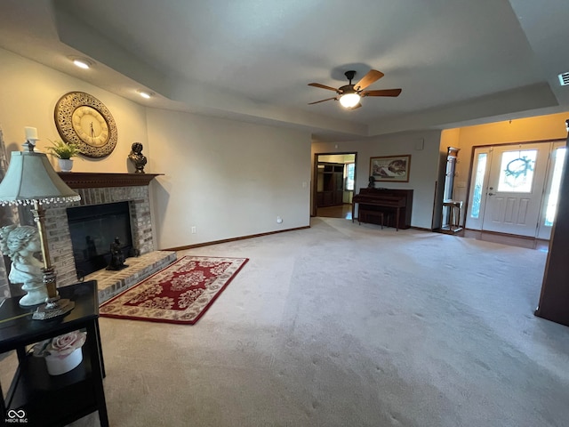 carpeted living room featuring ceiling fan, a fireplace, and a raised ceiling