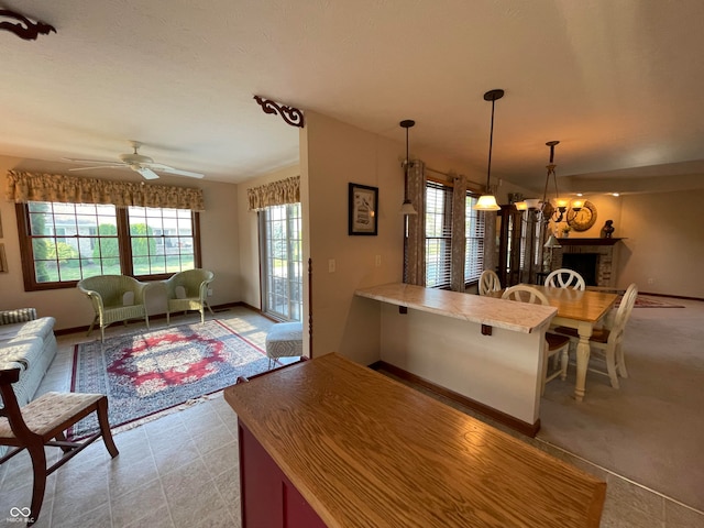 kitchen with kitchen peninsula, a breakfast bar area, ceiling fan, and pendant lighting