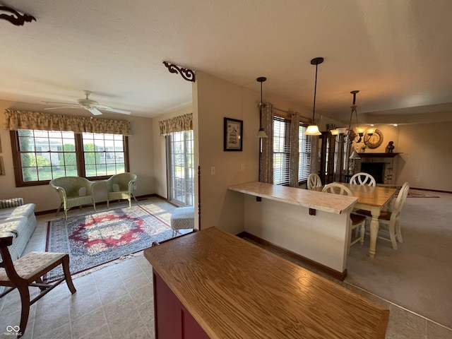 kitchen featuring a peninsula, a ceiling fan, open floor plan, light countertops, and pendant lighting