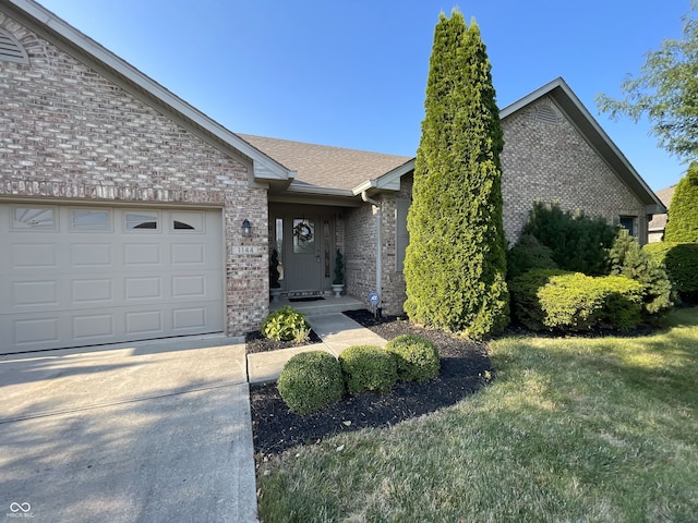 ranch-style house featuring a front yard, brick siding, an attached garage, and roof with shingles