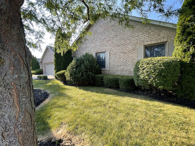 view of side of property with a garage, a yard, and brick siding