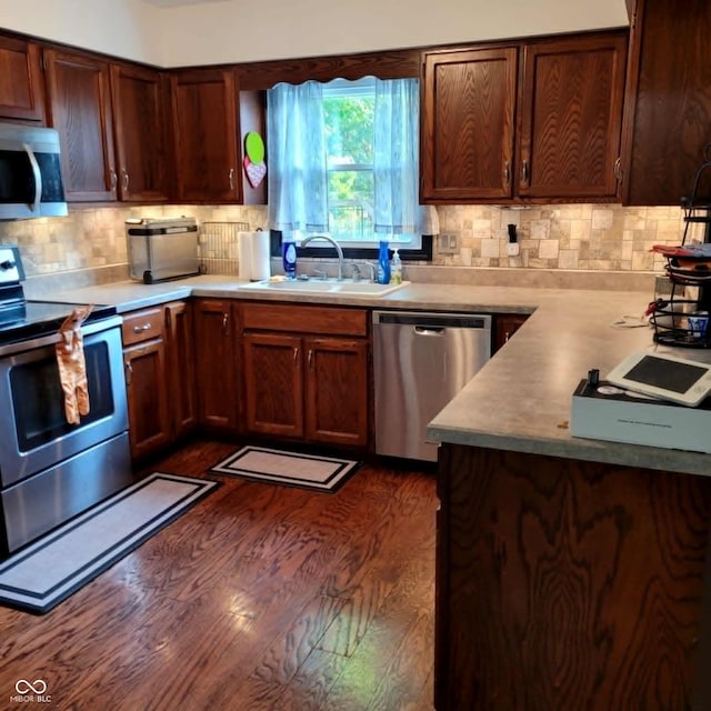 kitchen with sink, dark hardwood / wood-style flooring, decorative backsplash, and stainless steel appliances