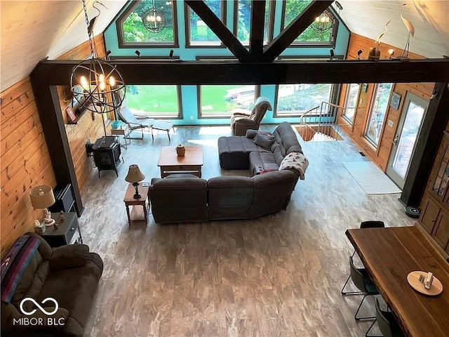 living room with high vaulted ceiling, an inviting chandelier, hardwood / wood-style flooring, and wooden walls