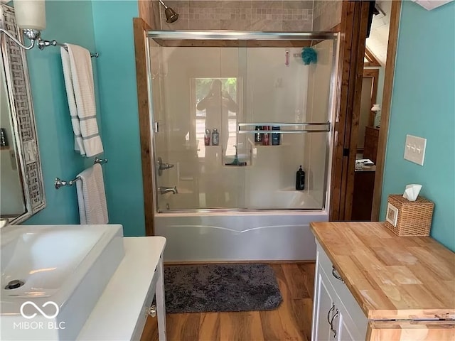 bathroom featuring bath / shower combo with glass door, wood-type flooring, and vanity