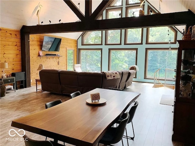 dining space featuring wood-type flooring, lofted ceiling with beams, and wooden walls