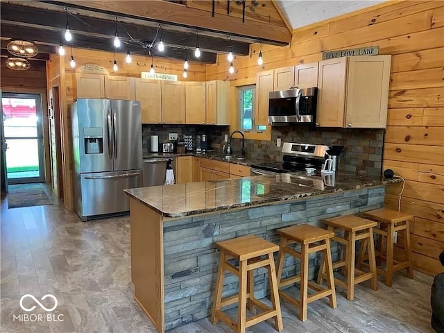 kitchen with light hardwood / wood-style floors, light brown cabinets, appliances with stainless steel finishes, and kitchen peninsula