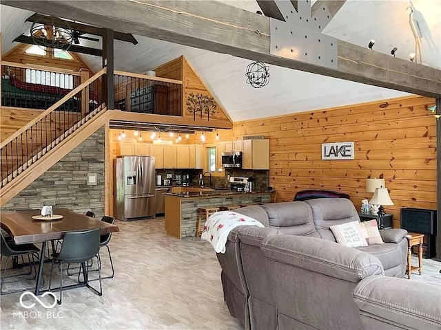 living room featuring sink, beam ceiling, high vaulted ceiling, wood walls, and ceiling fan