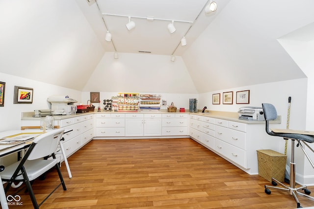 home office featuring rail lighting, light hardwood / wood-style floors, and lofted ceiling