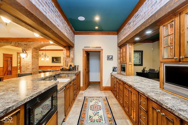 kitchen with light stone countertops, an inviting chandelier, hanging light fixtures, and sink