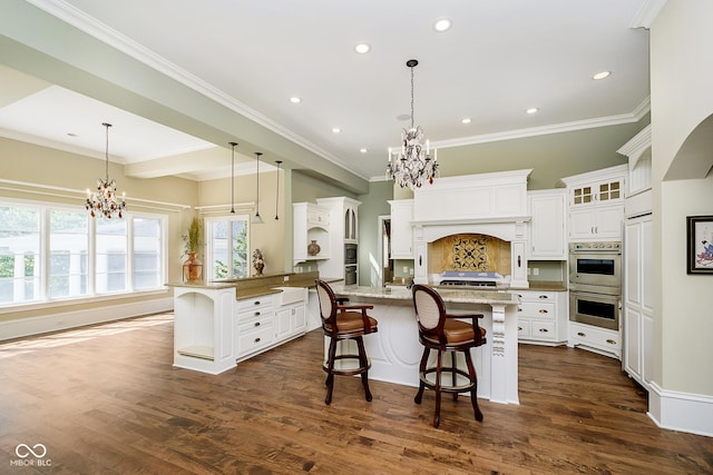 kitchen with white cabinets, a kitchen breakfast bar, dark wood-type flooring, and a notable chandelier