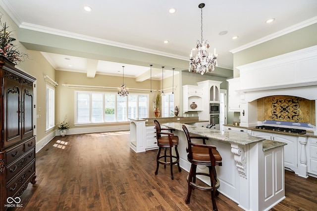 kitchen featuring white cabinets, dark hardwood / wood-style floors, hanging light fixtures, and a large island with sink