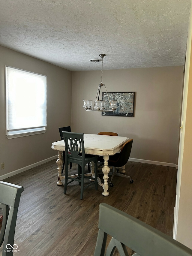 dining room with a textured ceiling and dark hardwood / wood-style flooring