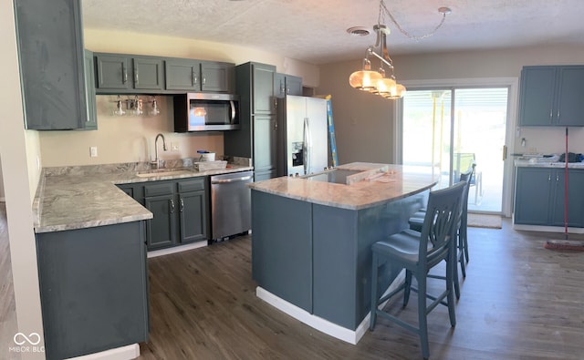 kitchen with appliances with stainless steel finishes, dark hardwood / wood-style floors, hanging light fixtures, and sink