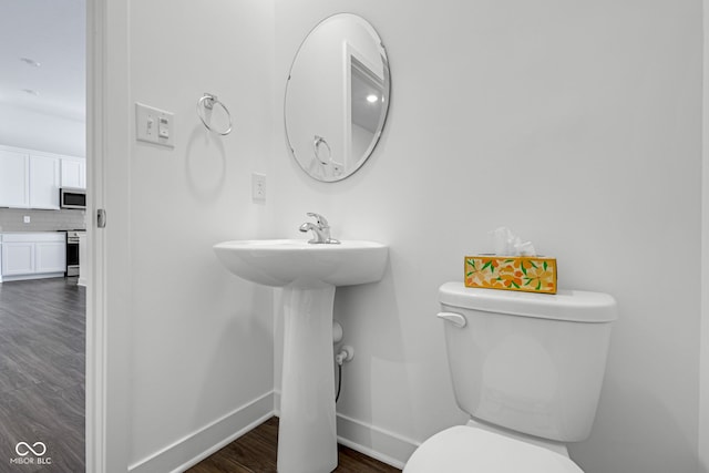 bathroom featuring wood-type flooring, tasteful backsplash, and toilet