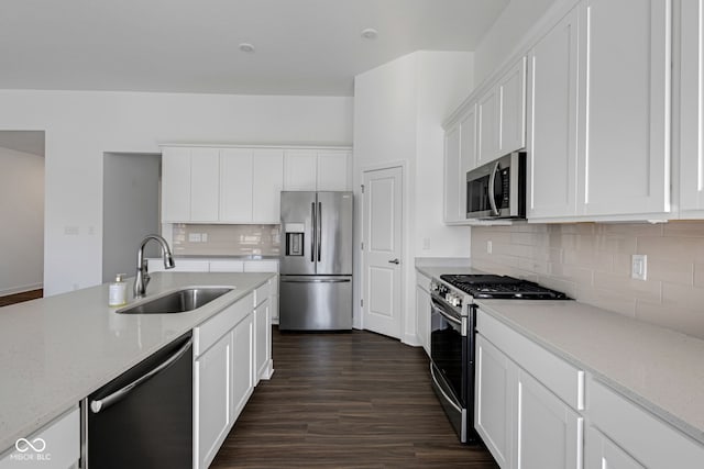 kitchen with appliances with stainless steel finishes, light stone counters, dark wood-type flooring, sink, and white cabinets