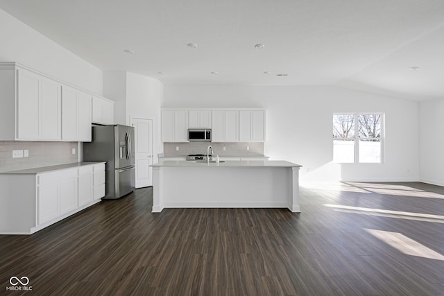 kitchen with dark hardwood / wood-style floors, decorative backsplash, stainless steel appliances, and vaulted ceiling