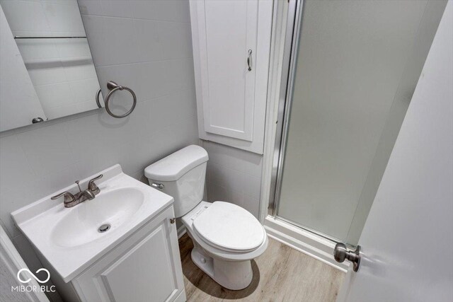 bathroom with vanity, walk in shower, tile walls, hardwood / wood-style floors, and toilet