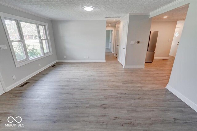 unfurnished room featuring a textured ceiling, light hardwood / wood-style flooring, and ornamental molding