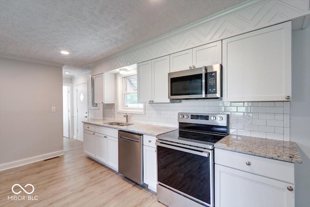 kitchen featuring white cabinetry, tasteful backsplash, stainless steel appliances, light hardwood / wood-style floors, and sink