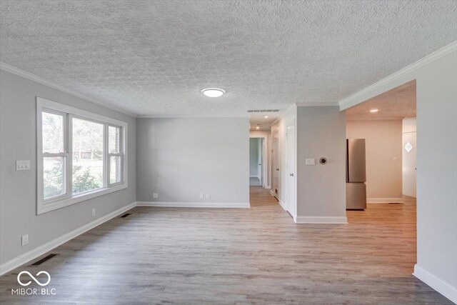 unfurnished room with ornamental molding, light hardwood / wood-style flooring, and a textured ceiling