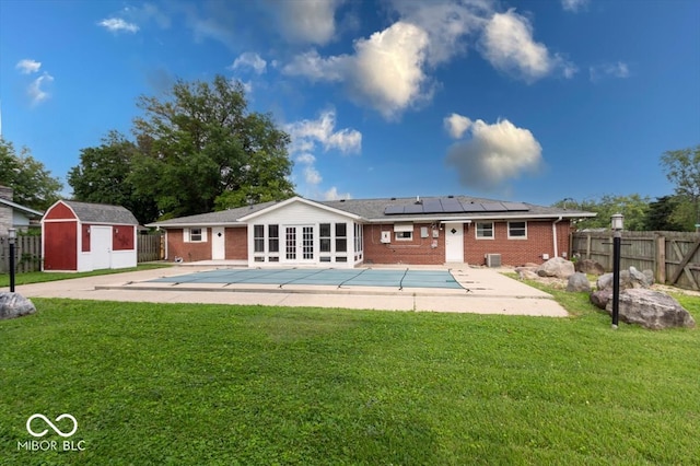 back of property featuring a shed, a yard, and a covered pool