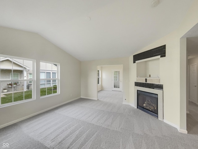 unfurnished living room with a tile fireplace, vaulted ceiling, and light carpet