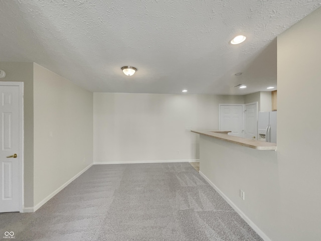 interior space featuring carpet flooring, a textured ceiling, and white fridge with ice dispenser